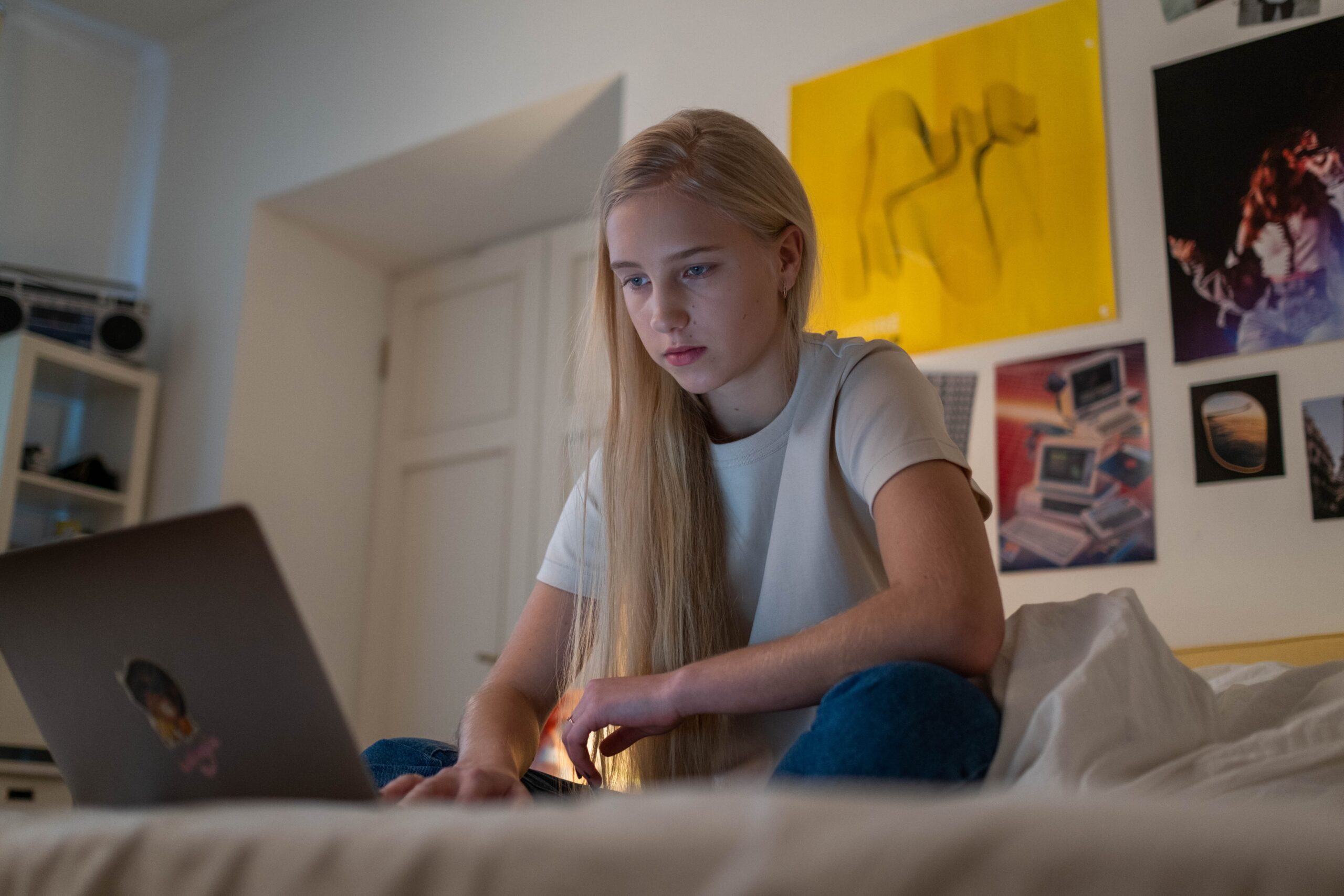young girl sitting on her bed on her laptop
